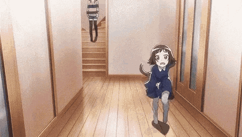 a little girl in a blue dress is running down a hallway next to a woman .