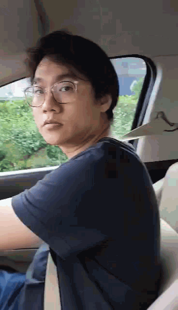 a man wearing glasses is sitting in a car looking out the window .