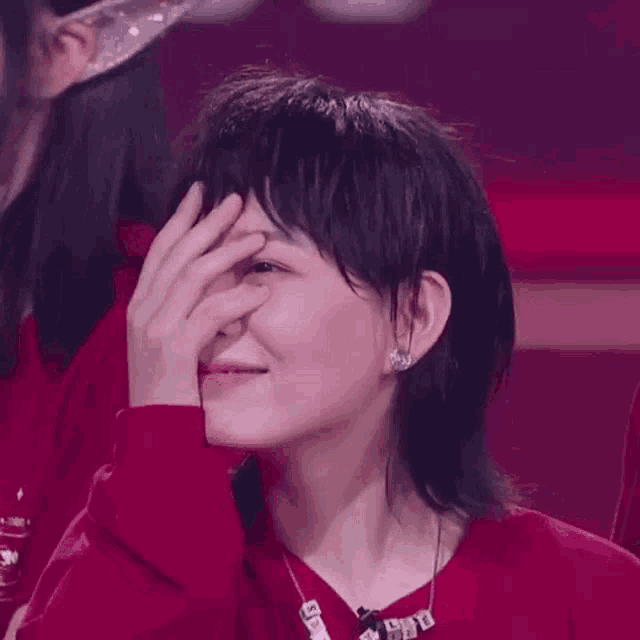 a woman is covering her face with her hand while sitting in a stadium .