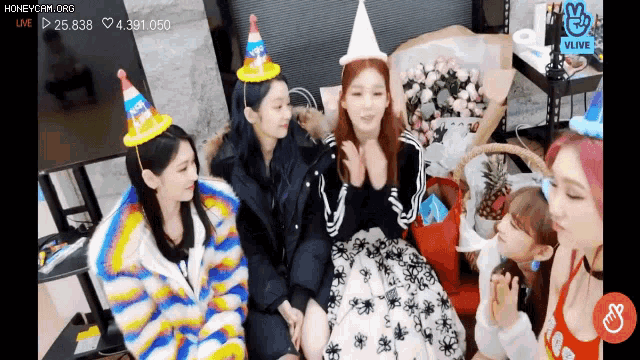 a group of girls wearing party hats are sitting next to each other in a room .