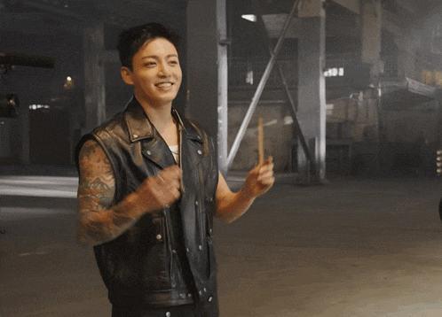 a man with a tattoo on his arm wearing a leather vest