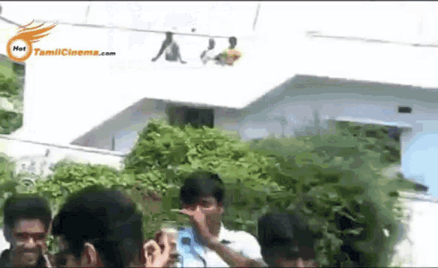 a group of people standing in front of a building with the website tamilcinema.com