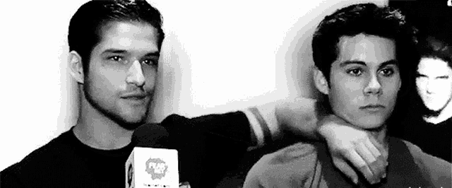 two men are standing next to each other in a black and white photo . one of the men is holding the other 's neck .