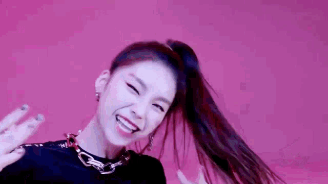 a close up of a woman 's face with a ponytail and a pink background .
