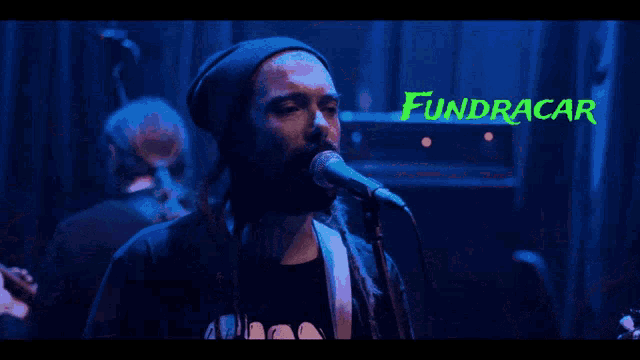 a man singing into a microphone with the word fundracar in green behind him