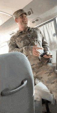a man in a military uniform is sitting on a bus and smiling