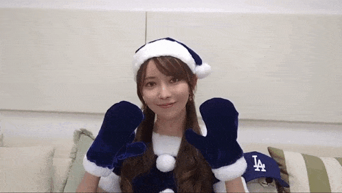 a woman is wearing a santa hat and mittens with the la logo on her hat