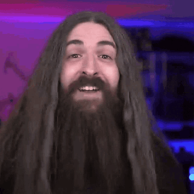 a man with long hair and a beard is making a really sign