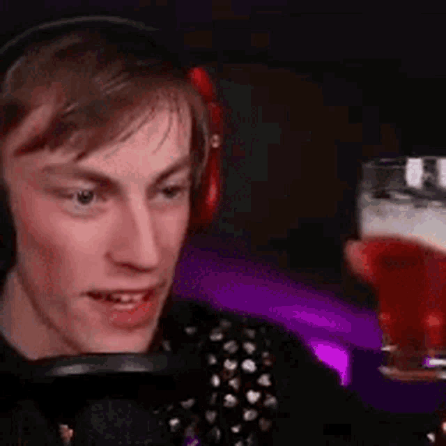 a young man is wearing headphones and holding a glass of beer .