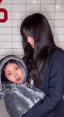 a woman is holding a child wrapped in a blanket with a hood