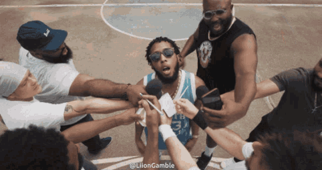 a group of men are gathered around a man wearing sunglasses and a jersey that says ' la ' on it
