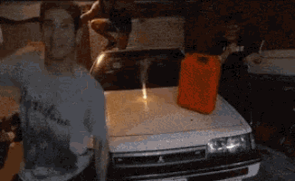a man standing next to a white car with a gas can in the trunk