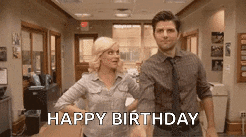 a man and a woman are dancing in an office and the man is saying happy birthday .