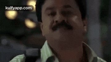 a man with a mustache is making a funny face and looking at the camera .
