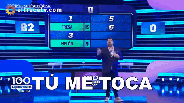 a man stands in front of a scoreboard that says " 100 tu me toca " on it