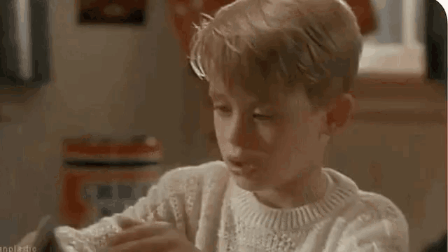 a young boy in a white sweater is playing a video game .