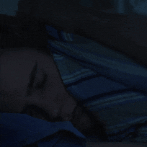 a man in a blue shirt is sleeping in a bed
