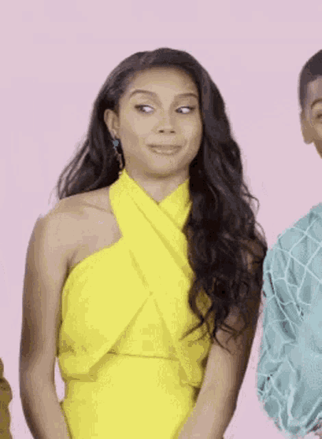 a woman in a yellow dress is making a funny face while standing next to two men .