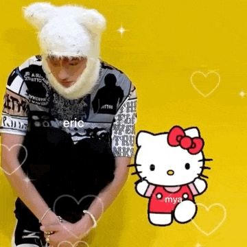 a man wearing a bear hat is kneeling next to a hello kitty doll .
