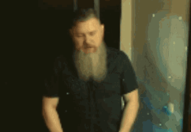 a man with a beard is standing with his arms crossed in front of a mirror