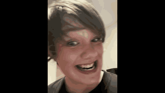a young boy with short hair is making a funny face with his mouth open