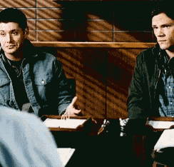 two men are sitting at a table with papers in front of them .