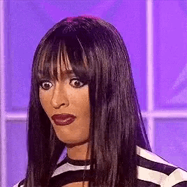 a woman with long black hair and a wig is making a funny face .