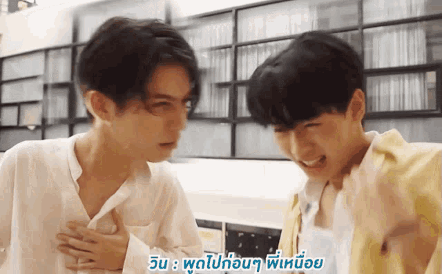 two young men are standing next to each other and one has his hand on the chest