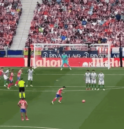 a soccer game is being played in front of a large mahou ad