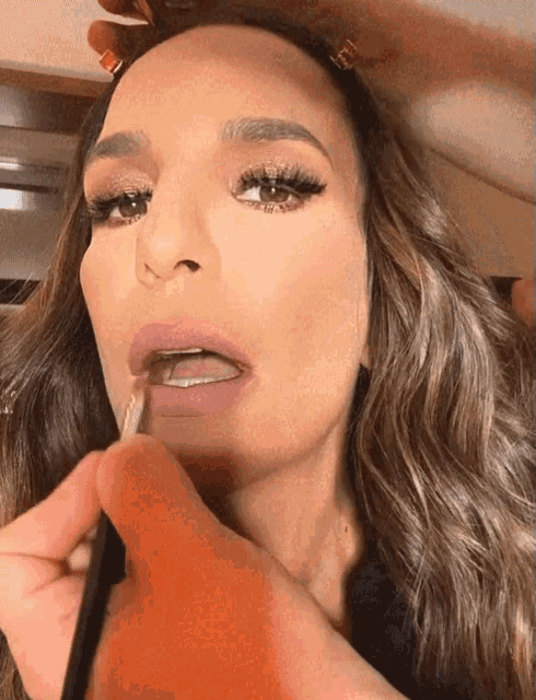 a woman is getting her lips painted with a pink lipstick