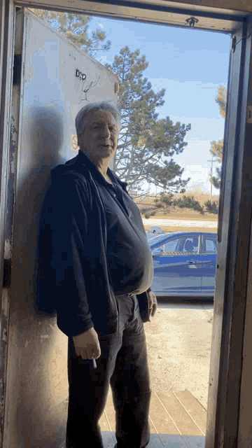 a man standing in a doorway with a sticker on the wall that says ' dp '