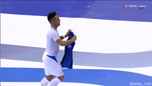 a man in a white shirt and blue shorts is holding a blue shirt in his hand