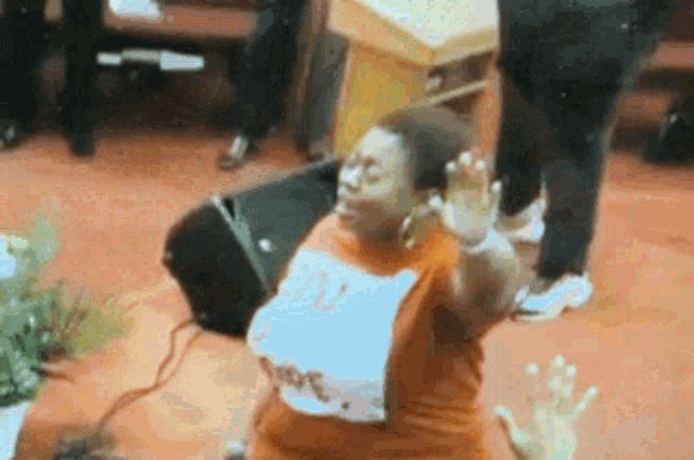 a woman in an orange shirt is dancing in a church with her hands up .
