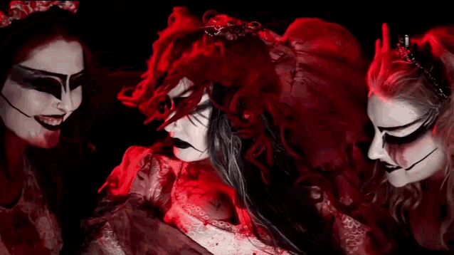 a woman with red hair and black makeup is surrounded by two other women .