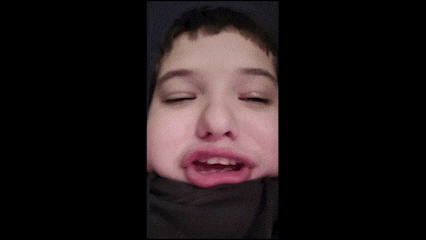 a close up of a young boy making a funny face .