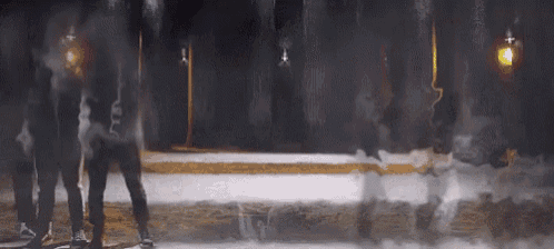 a group of people are standing in a dark room with smoke coming out of the walls .