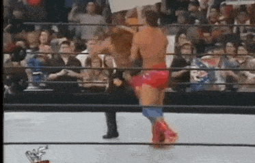a couple of men are wrestling in a ring in front of a crowd .