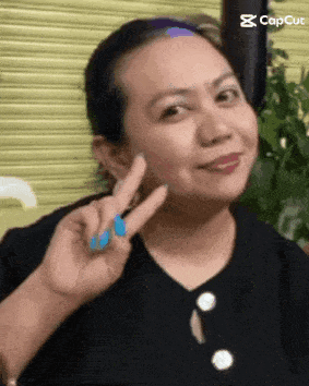 a woman is making a peace sign with her finger