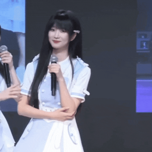 a girl with long black hair holding a microphone