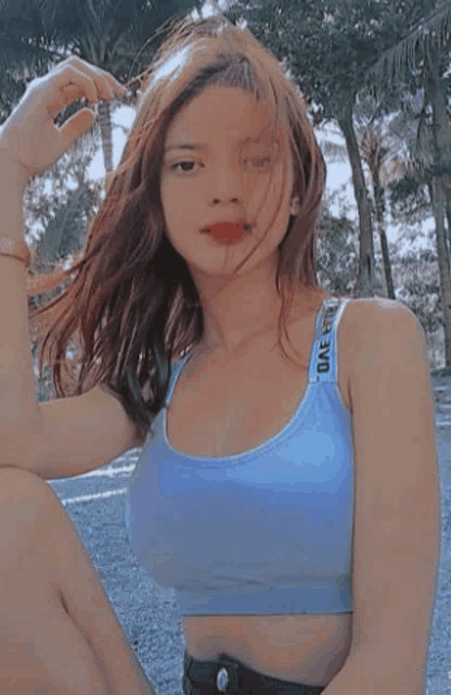 a woman wearing a blue crop top is sitting on the ground .