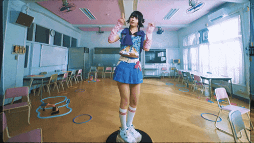 a girl in a blue skirt and pink gloves is standing in a room with tables and chairs