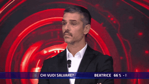 a man in a suit and white shirt stands in front of a red background with the words beatrice 66 % massimiliano 34 % below him