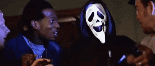 a group of people are standing around a man wearing a ghost face mask