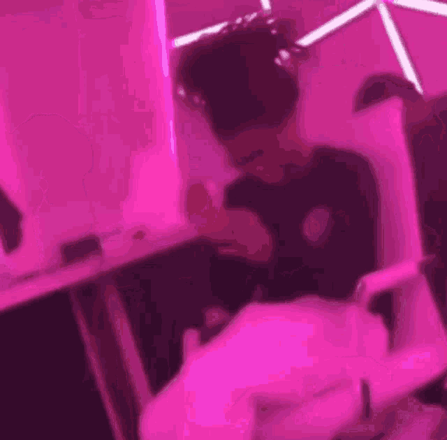 a man is sitting at a table in front of a pink wall .
