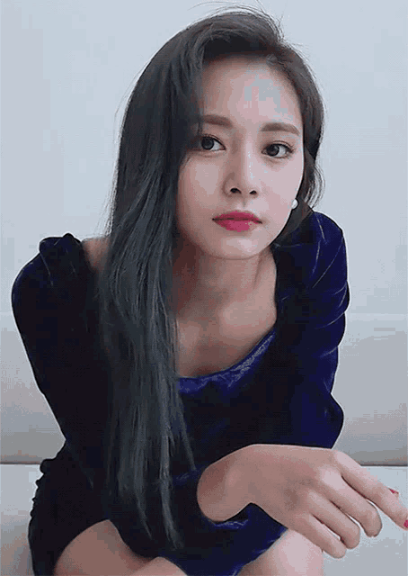 a woman in a blue velvet dress is sitting on a couch