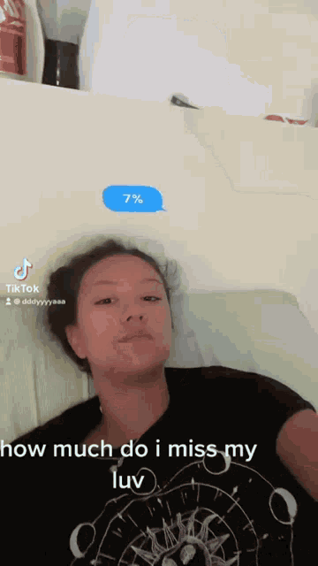 a woman in a black shirt is laying on a bed with a speech bubble that says 7%