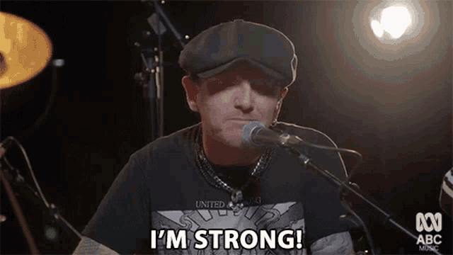 a man is singing into a microphone and says i 'm strong .