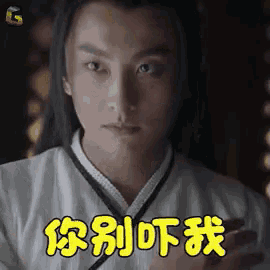 a man with long hair is holding a cell phone and making a funny face in chinese .