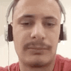 a man wearing headphones and a red shirt is taking a selfie .