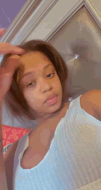 a young woman in a white tank top is taking a selfie
